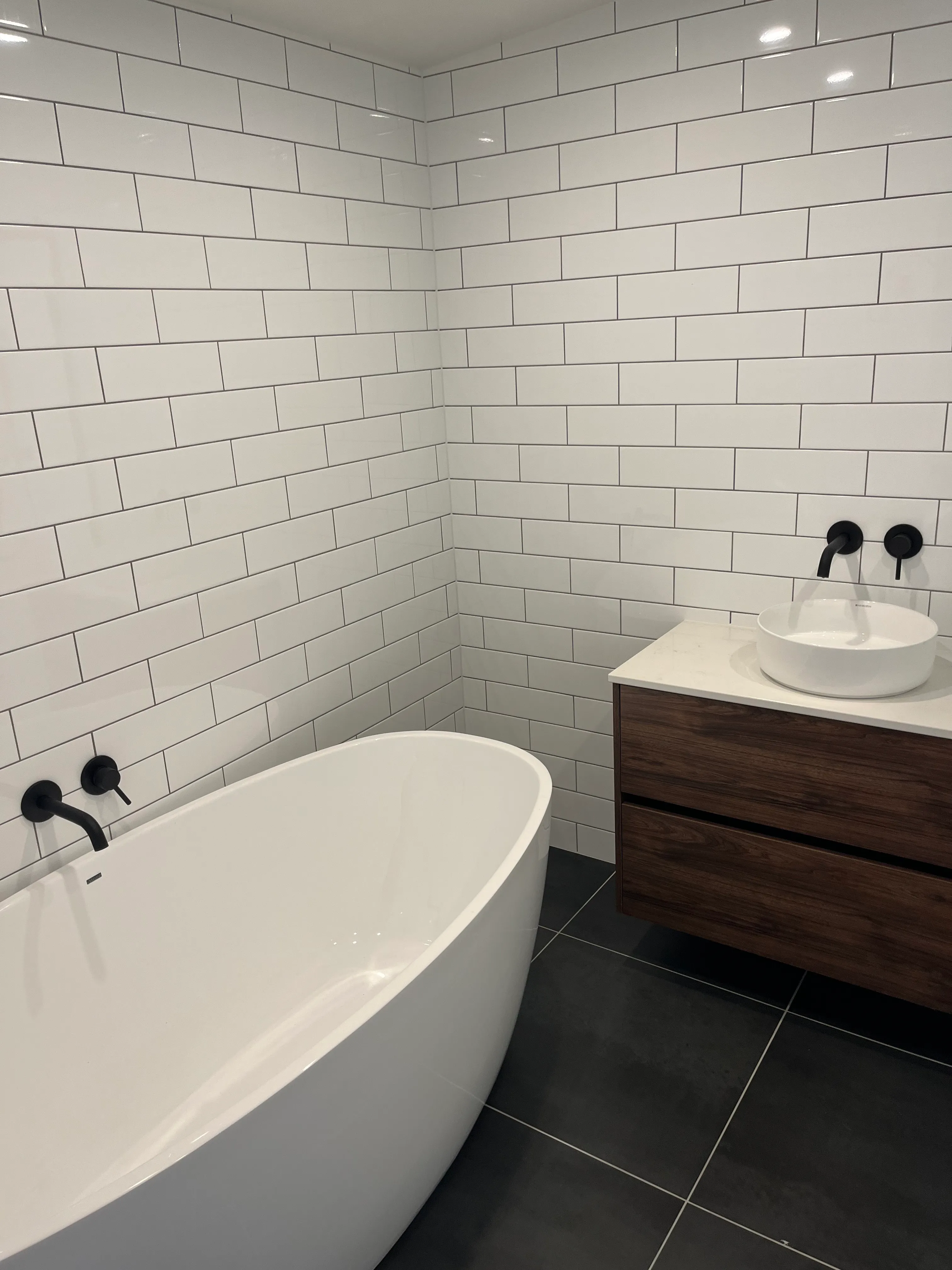 Spa-style bathroom with white soaking tub and black modern fixtures