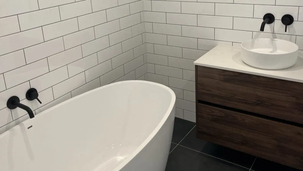 Modern bathroom with white subway tiles, soaking tub and dark wood vanity